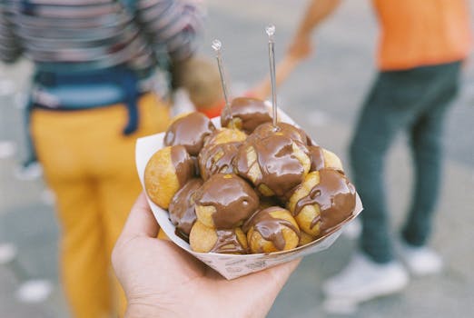 Sweet chocolate-covered pastry balls served outdoors in a street setting.